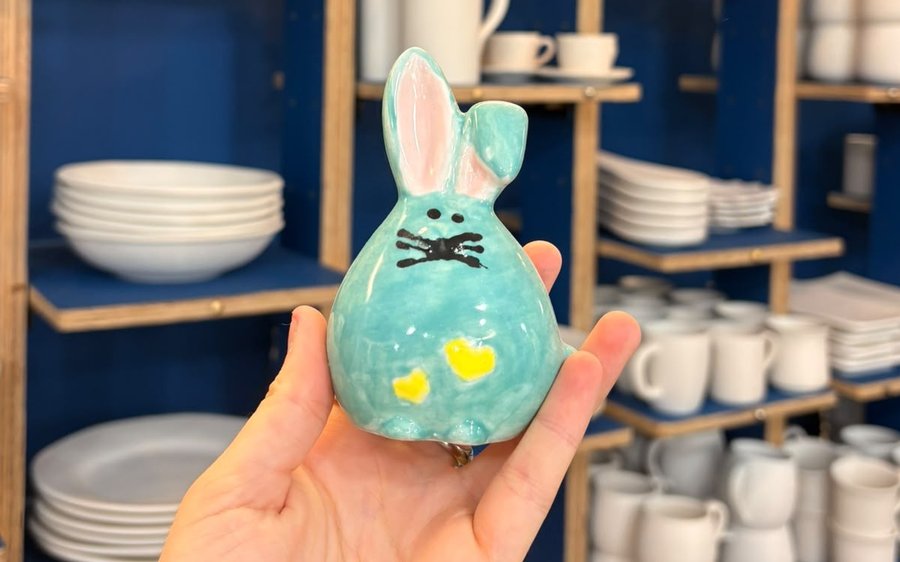 Petit lapin en céramique turquoise peint à la main, tenu dans une main